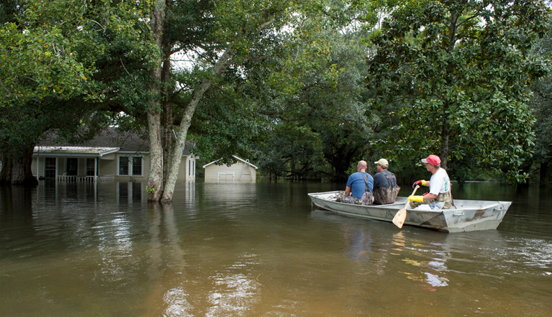 Residents paddle a boat towards their home that's still surrounded by floodwater in Prairieville, La. (Photo by J.T. Blatty/FEMA)