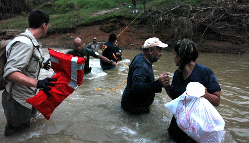 John Dobbins, a Red Cross medic, assists survivors as they cross the surging Dos Bocas river. Photo by Natalee Ebanks, courtesy of the Federal Emergency Management Agency