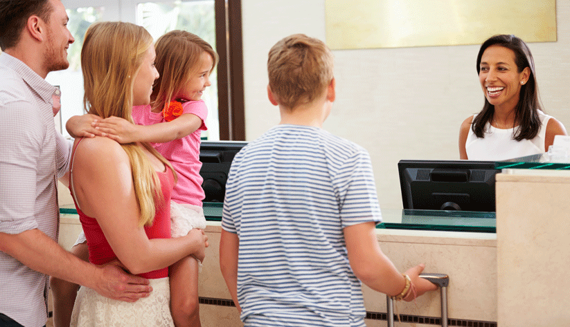 photograph of a family standing together and talking to an agent at a travel check-in desk