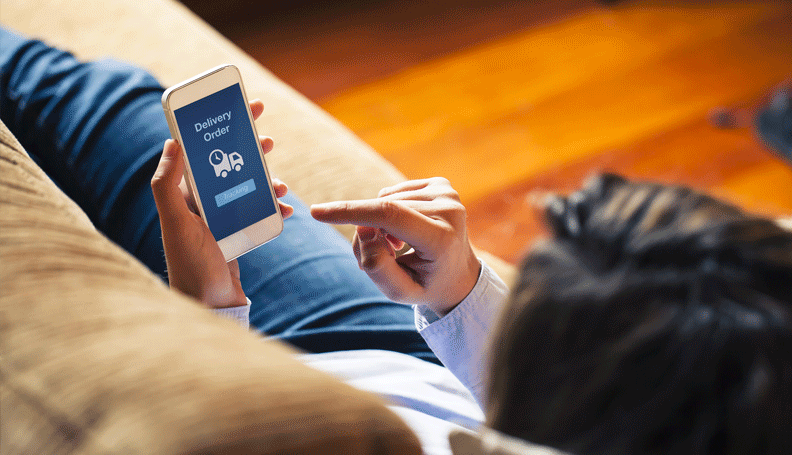 person sitting on couchwith finger poised to trigger a delivery order on a smart phone