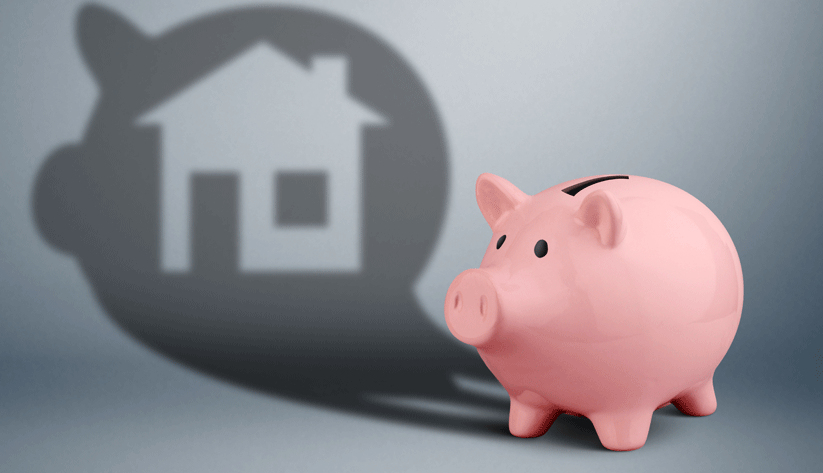 photograph of a pink piggy bank casting a shadow with the shape of a house cut out of it